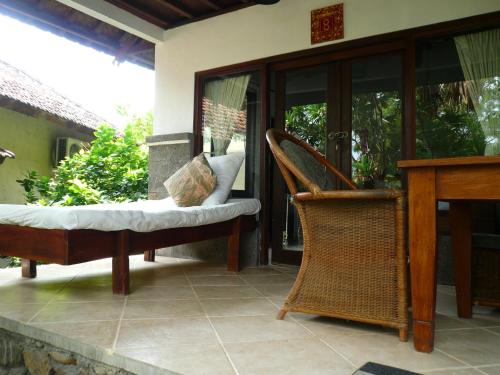 a porch with a chair and a table and a desk at Wawa Wewe II Villas in Amed