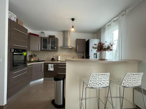 a kitchen with a counter and two stools in it at Disney en famille&Appart Calme et Spacieux in Magny-le-Hongre