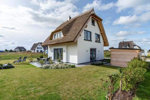 a house with a thatched roof and a yard at Maison Mer Baltique in Dranske