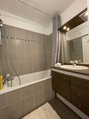 une salle de bain avec une baignoire, un lavabo et un miroir dans l'établissement Disney en famille&Appart Calme et Spacieux, à Magny-le-Hongre