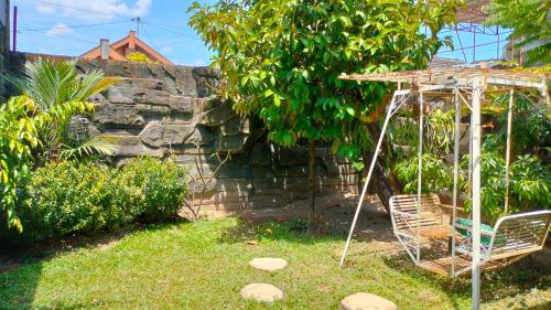 Eine Schaukel in einem Garten neben einer Steinmauer in der Unterkunft Purikafilla Homestay in Timuran