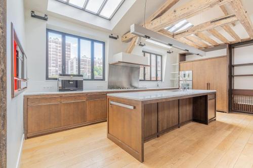 une grande cuisine avec des placards en bois et une grande fenêtre dans l'établissement Hôtel particulier dans le 17ème arondissement, à Paris