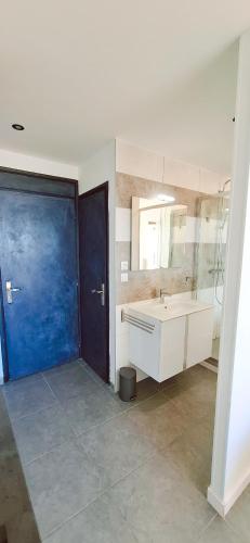 La salle de bains est pourvue d'un lavabo et d'une porte bleue. dans l'établissement Village naturiste Cap d'Agde le Cap Pleasure, au Cap d'Agde