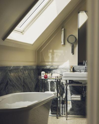 a bathroom with a tub and a sink and a skylight at Hôtel Balzac Paris & Spa Ikoï in Paris
