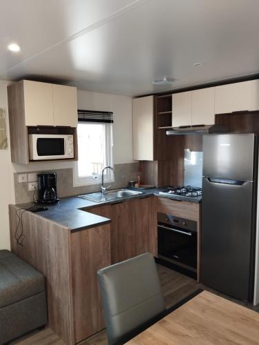 a kitchen with wooden cabinets and a stainless steel refrigerator at mobile home photovoltaique st jean de monts in Saint-Jean-de-Monts
