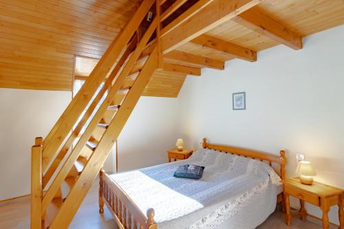 ein Schlafzimmer mit einem Bett und einer Holztreppe in der Unterkunft Le Petit Pech in Le Sirey