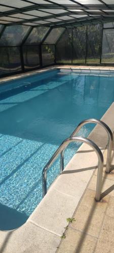 - une piscine bleue avec une main courante en métal dans l'établissement maison de campagne toute équipée 5km de Thoiry, à Saulx-Marchais