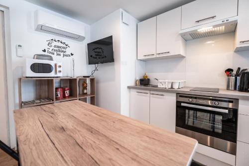 a kitchen with white cabinets and a wooden table at Maison Galine - Piscine & Aire de Jeux - Maison de campagne in Beauvais-sur-Tescou