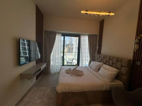 a bedroom with a bed and a television and a window at Stunning Studio in Meydan Azizi 42 in Dubai