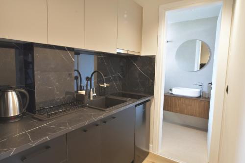 a kitchen with white cabinets and a sink and a mirror at Feel Athens Studios at Monastiraki in Athens