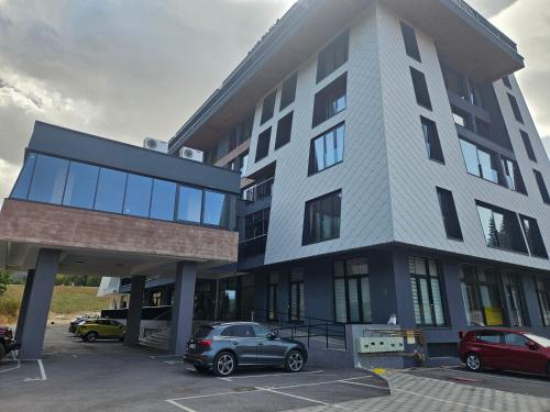 a building with a car parked in a parking lot at Mountain Magic Bjelašnica in Bjelašnica