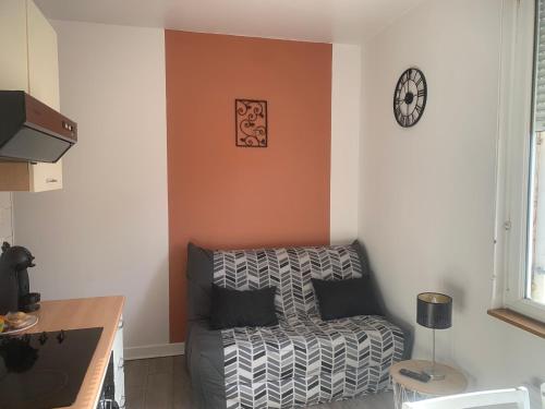 un salon avec un canapé et une horloge au mur dans l'établissement Le petit Bailleux, à Braine