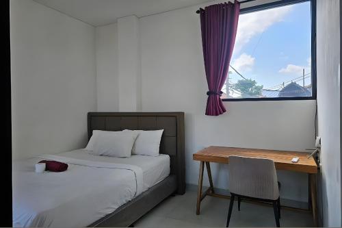 a bedroom with a bed and a desk and a window at Margarita Apartment and Coworking Canggu in Canggu