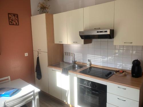 une cuisine avec des armoires blanches, un évier et une cuisinière dans l'établissement Le petit Bailleux, à Braine