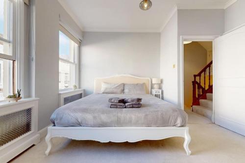 a white bedroom with a white bed and a window at Prime Location Prince's Gate Mews 4BD 3 BATH in London