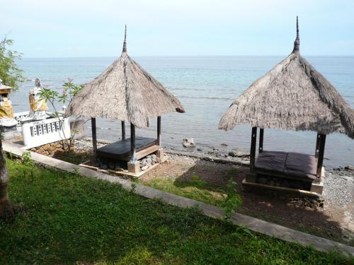 two chairs and umbrellas on a beach with the ocean at Wawa Wewe II Villas in Amed