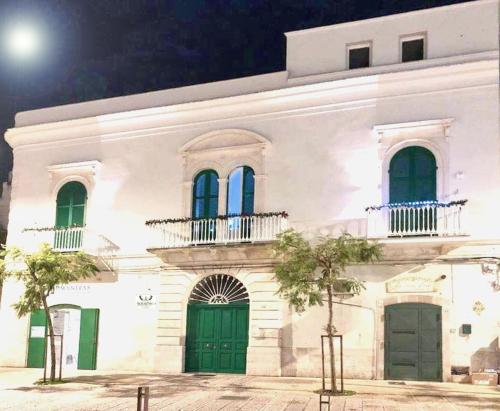 un edificio blanco con puertas y ventanas verdes por la noche en AuGuStea, en Sannicandro di Bari