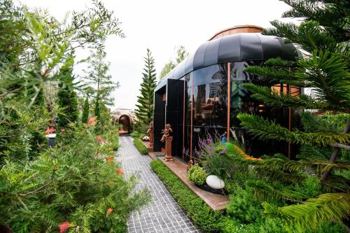 a glass house with a walkway in a garden at The One Smart Living in Bangkok