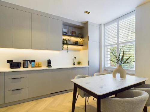 a kitchen with white cabinets and a table and chairs at Be London - Maida Vale Residences in London