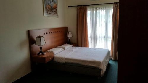 a bedroom with a bed with a lamp and a window at T & H Vacation Condo @Marina Court in Kota Kinabalu