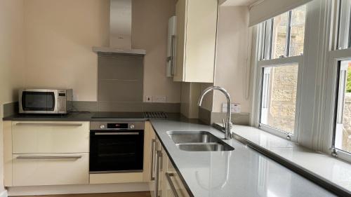 a white kitchen with a sink and a microwave at 19 Snowdon Apartment in Stirling