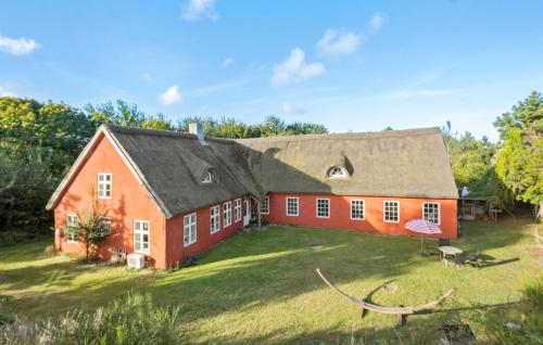 eine orangefarbene Scheune mit schwarzem Dach auf einer Wiese in der Unterkunft Stunning Home In Sjællands Odde in Yderby