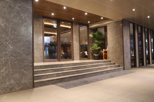 a lobby of a building with stairs and windows at Chiayi Maison de Chine Hotel in Chiayi City