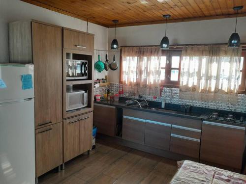 a kitchen with wooden cabinets and a white refrigerator at Casa BuLuMAR in Conventos