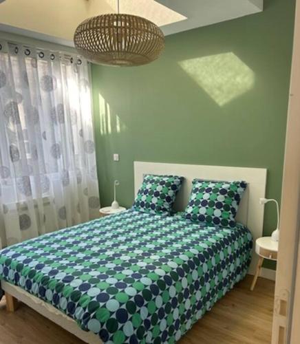 - une chambre dotée d'un lit vert et blanc avec deux oreillers dans l'établissement Appartement de standing Face Mer, au Croisic