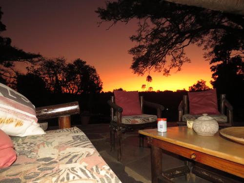 a room with chairs and a table with a sunset in the background at Thokozani Lodge in White River