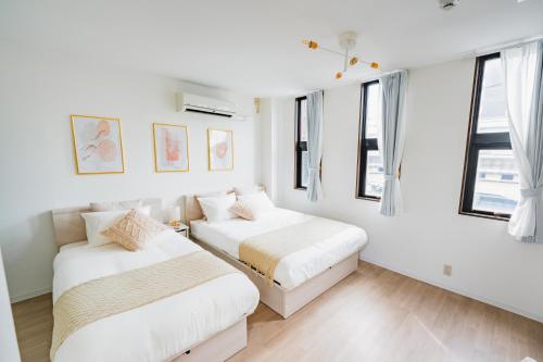 two beds in a room with white walls and windows at Tamagawa House 2BR in Osaka