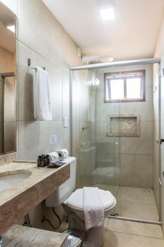 a bathroom with a toilet and a glass shower at Pousada Sunbrazil in Jericoacoara