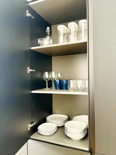 a pantry with plates and glasses on shelves at Zeus at Como Duomo - Luxury Collection in Como