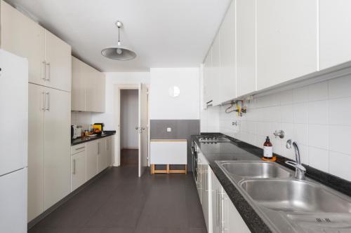 a kitchen with white cabinets and stainless steel sinks at Baixa Chiado LUXURY BEDROOMS in Lisbon