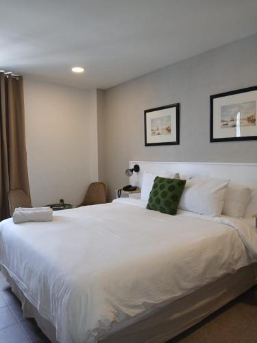 a bedroom with a large white bed with two chairs at San Marco Hotel Curacao & Casino in Willemstad