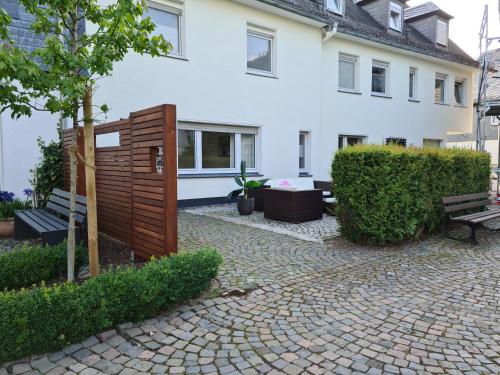 ein weißes Haus mit einer Bank und einem Baum in der Unterkunft Pilgrims "Bert" moderne Wohnung 2 SZ top wifi in Meschede