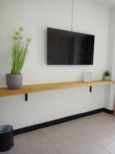 a flat screen tv on a wall with a wooden shelf at San Marco Hotel Curacao & Casino in Willemstad