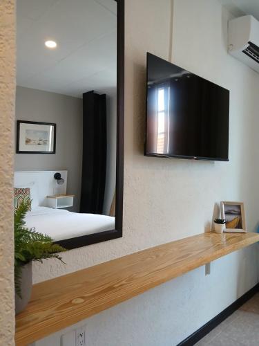 a mirror on a wall with a bed and a television at San Marco Hotel Curacao & Casino in Willemstad