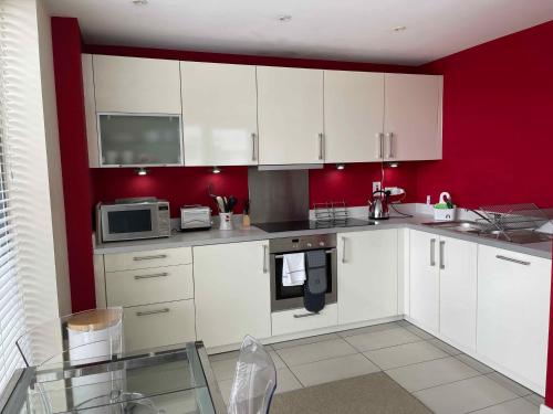a kitchen with white cabinets and a red wall at Glasgow Harbour River West End in Glasgow
