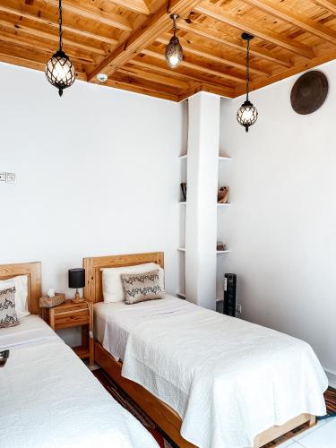 two beds in a room with wooden ceilings at Riad Al Manara in Essaouira