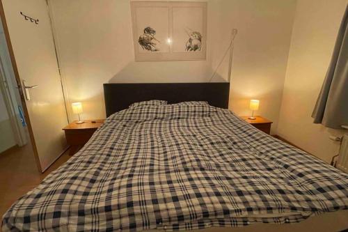 a bed with a checkered blanket in a bedroom at Centre Hilversum, 20 minutes train to Amsterdam in Hilversum