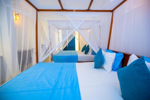 a bedroom with a bed with blue and white pillows at Hotel Zeilan Sunset Point in Unawatuna