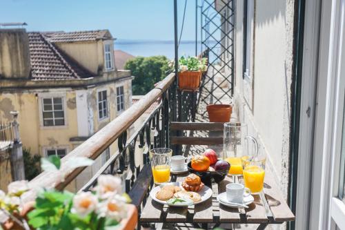a breakfast table on a balcony with breakfast foods and orange juice at Chiado Prestige View Apartment in Lisbon