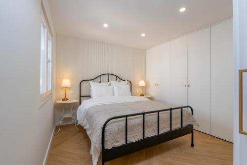 una camera da letto con un letto con pareti bianche e due lampade di Sintra premium Villa a Sintra
