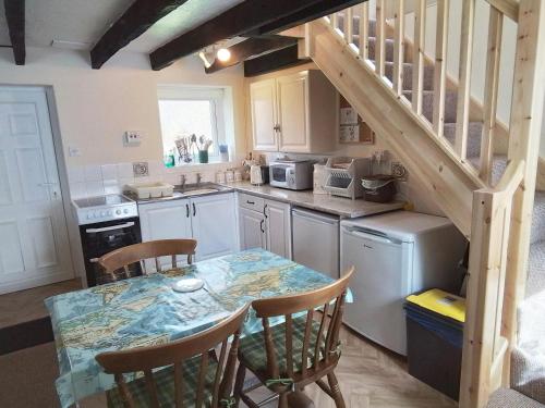 une cuisine avec une table et des chaises ainsi qu'un escalier dans l'établissement Dairy Cottage Newcastle Emlyn, à Newcastle Emlyn