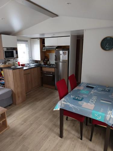 une cuisine avec une table et deux chaises rouges dans l'établissement Bungalow chaleureux à Saint-Brevin-les-Pins 40 m² piscine partagée, à Saint-Brévin-les-Pins