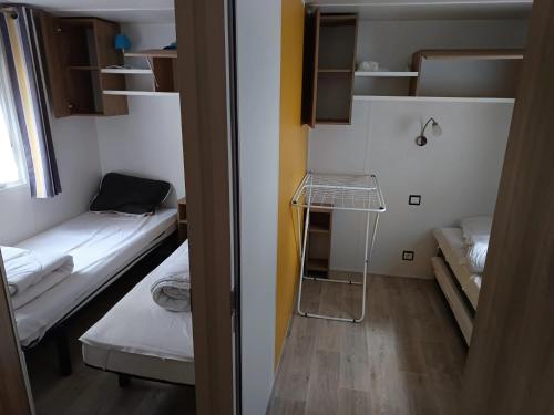 Cette petite chambre comprend 2 lits et une étagère. dans l'établissement Bungalow chaleureux à Saint-Brevin-les-Pins 40 m² piscine partagée, à Saint-Brévin-les-Pins