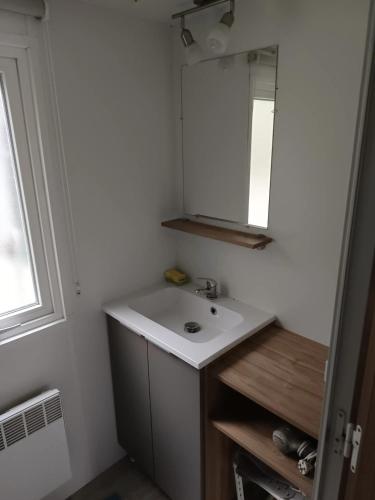 une salle de bain avec un lavabo blanc et un miroir dans l'établissement Bungalow chaleureux à Saint-Brevin-les-Pins 40 m² piscine partagée, à Saint-Brévin-les-Pins