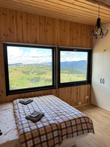 a bedroom with a bed and two large windows at Cabană Vinkiș in Măguri-Răcătău