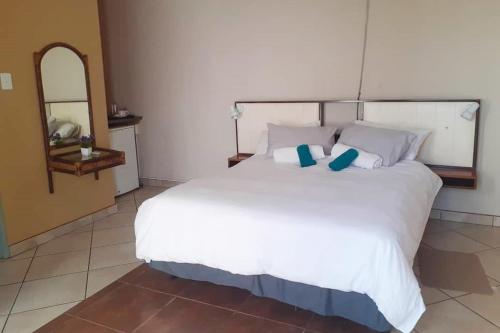 a bedroom with a large white bed with blue pillows at Ochsenwagen Pension Hotel in Rehoboth